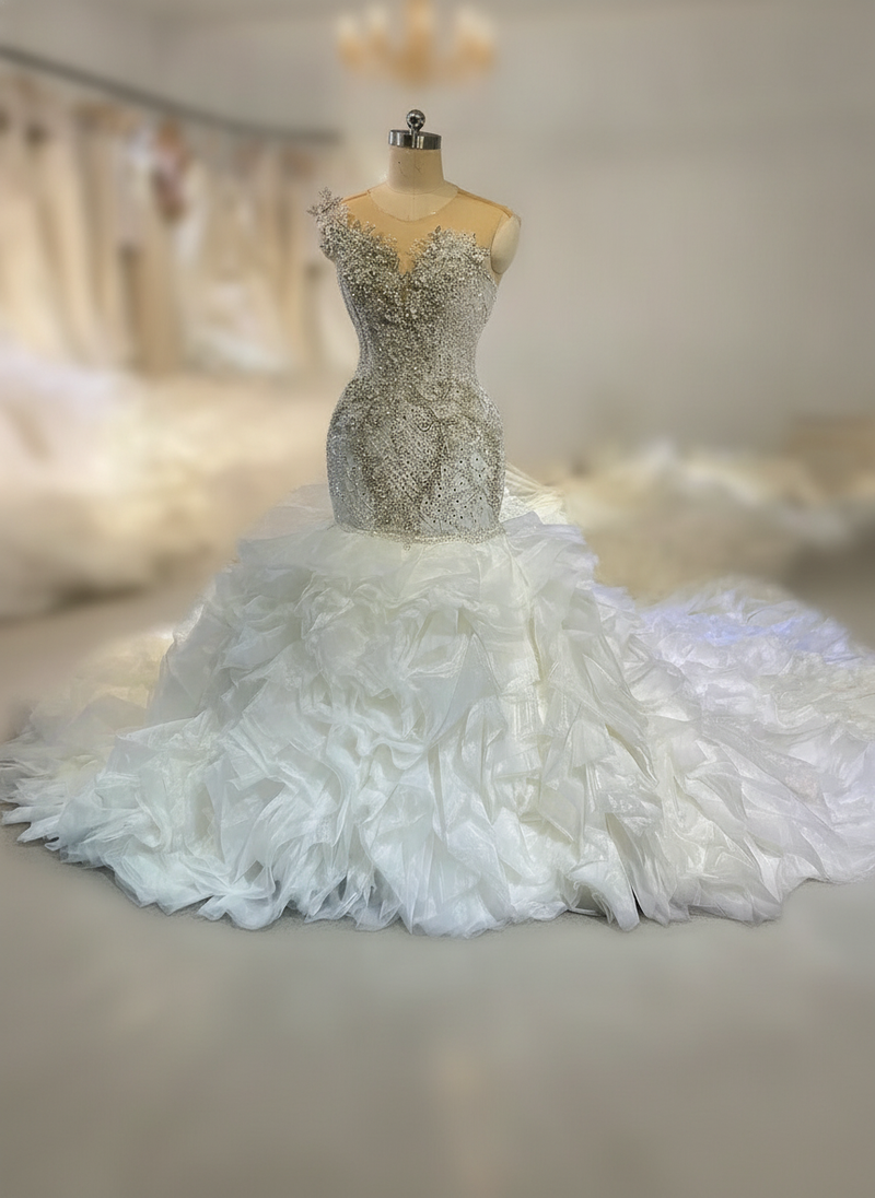 Custom ruffle mermaid wedding dress by Amanda Novias, featuring a 2-in-1 design, against a softly lit backdrop.